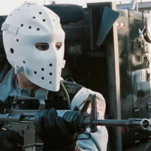 A man wearing a mask aims his gun in Heat.