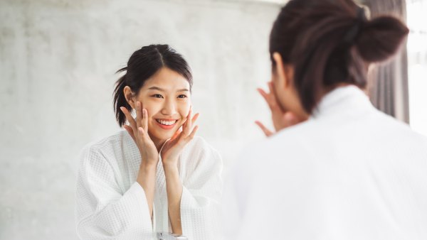 Asian woman cleaning face front of mirror, skin care and cosmetic removal concept