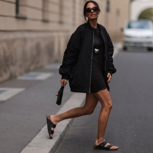 BERLIN, GERMANY - AUGUST 23: Anna Winter wearing Birkenstock black sandals, Frankie Shop black oversized statement bomber jacket, The Good statement silver heart chain, ByFar black mini bag, Weekday brown transparent mini dress and Bottega Veneta brown shades on August 23, 2022 in Berlin, Germany. (Photo by Jeremy Moeller/Getty Images)