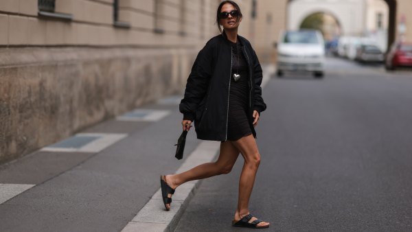 BERLIN, GERMANY - AUGUST 23: Anna Winter wearing Birkenstock black sandals, Frankie Shop black oversized statement bomber jacket, The Good statement silver heart chain, ByFar black mini bag, Weekday brown transparent mini dress and Bottega Veneta brown shades on August 23, 2022 in Berlin, Germany. (Photo by Jeremy Moeller/Getty Images)