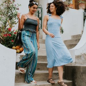 Two beautiful young woman descend a set of concrete steps from European-style apartments as they have a conversation.