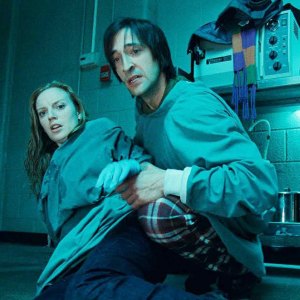 A man and a woman lean back in terror in Splice.