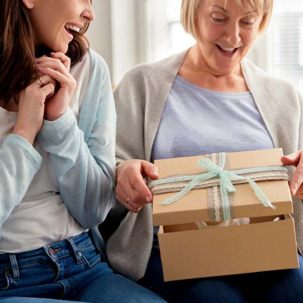 Excited adult daughter waiting for mom to open the gift