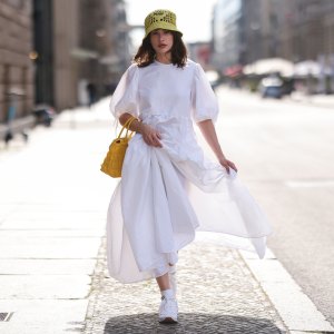 Lena Naumann wearing New Balance x Miu Miu white sneaker, Cecilie Bahnsen white maxi dress, Prada kiwi green bucket hat, Prada yellow bag on May 31, 2022 in Berlin, Germany.
