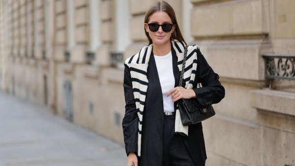 Diane Batoukina wears black large sunglasses, a white halter-neck tank-top from Anine Bing, a black blazer jacket from Massimo Dutti, a white latte and black striped print pattern wool pullover from Zara, a black shiny grained leather small Kelly belt from Hermes, black suit shorts from Massimo Dutti, a black shiny leather quilted Timeless handbag from Chanel, during a street style fashion photo session, on April 28, 2023 in Paris, France.