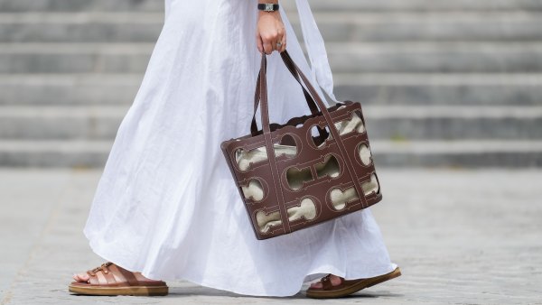 Gabriella Berdugo wears a Cartier watch, a white linen gathered dress from kalita, a brown summer bag from Carolina Herrera in brown leather, brown leather sandals from Celine, during a street style fashion photo session, on May 12, 2024 in Paris, France.