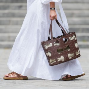 Gabriella Berdugo wears a Cartier watch, a white linen gathered dress from kalita, a brown summer bag from Carolina Herrera in brown leather, brown leather sandals from Celine, during a street style fashion photo session, on May 12, 2024 in Paris, France.