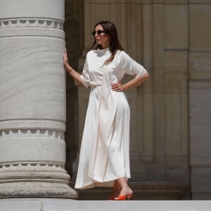 Gabriella Berdugo wears sunglasses, a white long gathered dress with a scarf from Gestuz, red kitten heels mule shoes with open toe from Age of Innocence, during a street style fashion photo session, on May 16, 2024 in Paris, France.