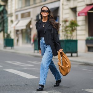 PARIS, FRANCE - APRIL 29: Tamara Kalinic wears black Sestini sunglasses, gold earrings, a black t-shirt, a black oversized ripped Margiela blazer jacket, a gold ring, blue faded denim oversized ripped Margiela jeans pants, a brown shiny leather braided Jodie Petit Bottega Veneta handbag, black shiny leather pointed heels Bottega Veneta ankle boots, on April 29, 2021 in Paris, France. (Photo by Edward Berthelot/Getty Images)