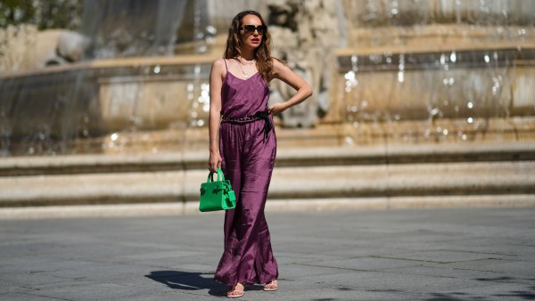 PARIS, FRANCE - MARCH 30: Ophélie Duvillard wears sunglasses, a necklace, a purple satin silky shiny jumpsuit from Mes Demoiselles with a tank top upper part and a lower part made of flared flowing pants, a Chanel belt, a neon green leather bag from Le Tanneur, shoes from Zara, on March 30, 2021 in Paris, France. (Photo by Edward Berthelot/Getty Images)