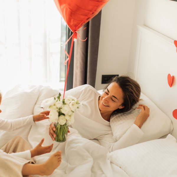 Little Daughter wakes up mother and Giving Gifts for her in Bed. - stock photo