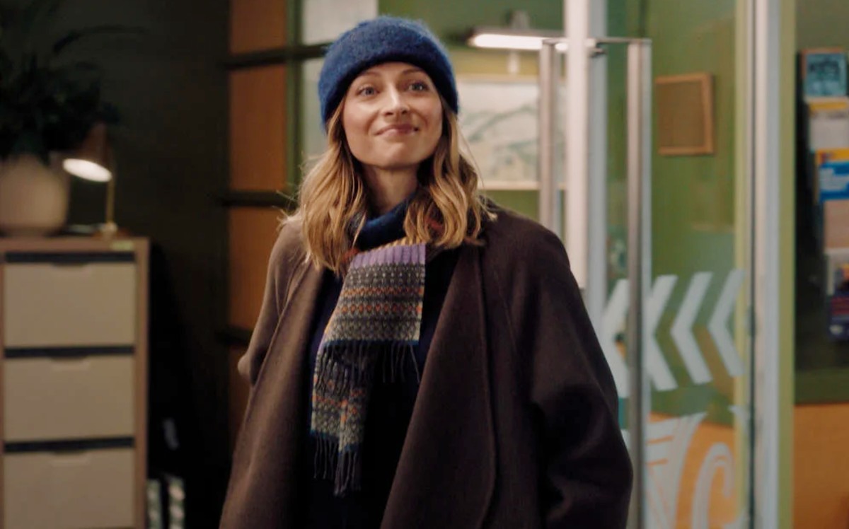 A woman in a knit hat smiles in A Remarkable Place to Die.