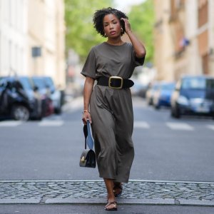 PARIS, FRANCE - MAY 20: Ellie Delphine wears golden earrings, a green khaki t-shirt dress from COS, a black leather bag from Neous, a black leather large buckle belt / wide waist belt from Source Unknown, jeweled leather sandals / black and gold leather sandals from Zara, during a street style fashion photo session, on May 20, 2024 in Paris, France. (Photo by Edward Berthelot/Getty Images)