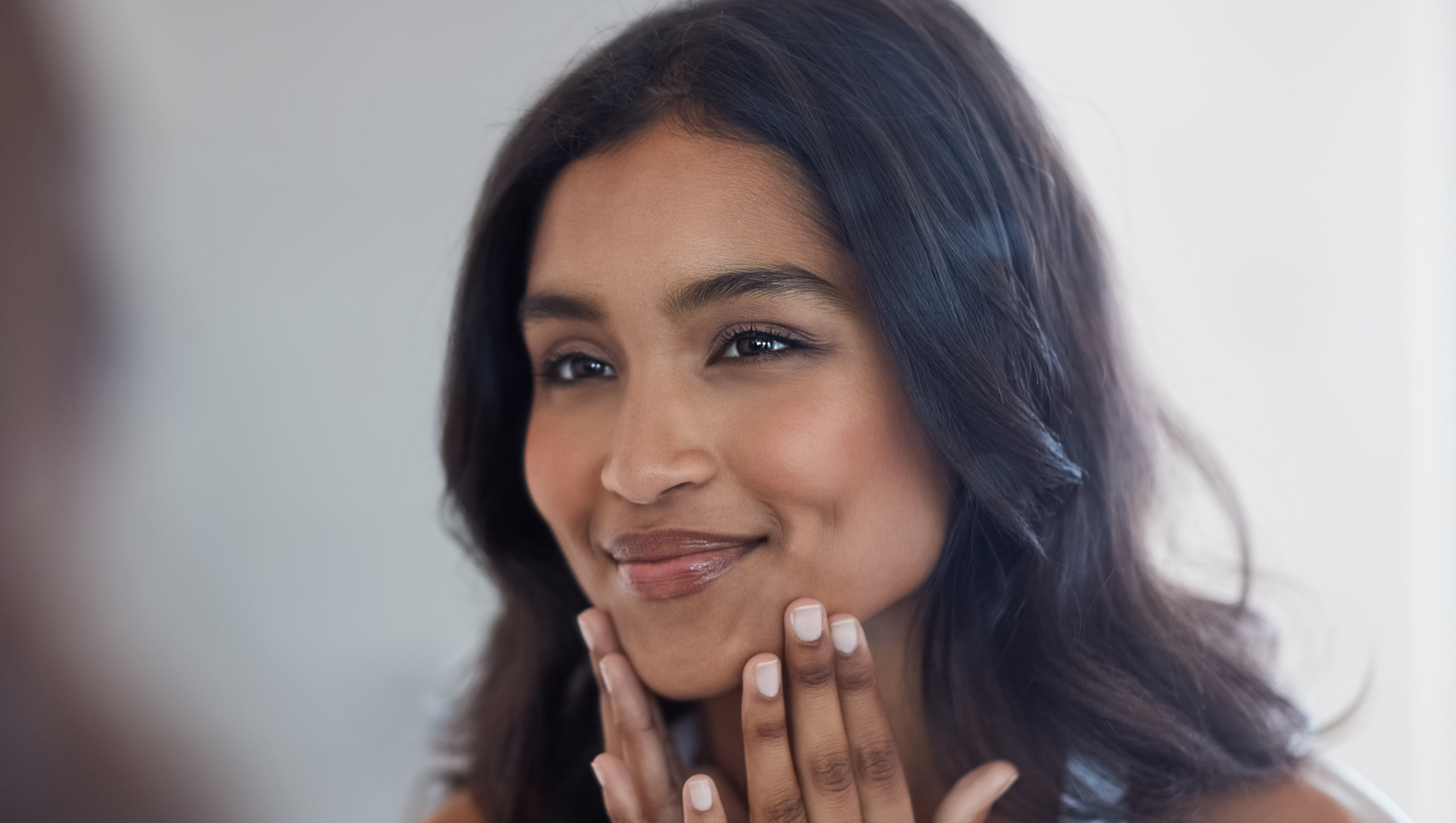 Shot of a beautiful young woman admiring herself in the mirror at home