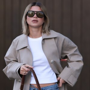BERLIN, GERMANY - APRIL 01: Sophia Geiss seen wearing Vehla Eyewear black / brown dark sunglasses, Drykorn white cotton basic casual cropped top, Meotine beige oversized trench coat adds effortless elegance, COS blue denim oversized, loose-fitting, wide-leg jeans with a drawstring waist enhance the relaxed vibe and a brown suede leather vintage bag complements the western aesthetic, on April 01, 2025 in Berlin, Germany. (Photo by Jeremy Moeller/Getty Images)