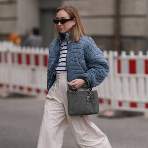 BERLIN, GERMANY - APRIL 04: Sonia Lyson seen wearing Jacquemus black sunglasses, Zara white striped cotton t-shirt, Khrisjoy blue denim striped short jacket, COS creamy white / beige linen long pants, Dior grey denim fabric vintage Lady Dior bag and Zara shiny black leather ballerinas, on April 04, 2024 in Berlin, Germany. (Photo by Jeremy Moeller/Getty Images)