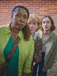 Three women lean near a brick wall in The Marlow Murder Club.