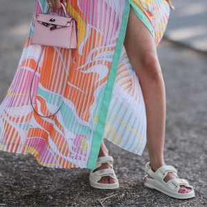 Mandy Bork seen wearing a colorful buttoned / pleated / sleeveless long dress from Emilio Pucci, a pale pink leather Hermes Kelly mini bag, gold diamond Cartier Love bracelet, a gold Cartier Juste Un Clou bracelet and white creme sandals from Chanel, during Paris Fashion Week - Haute Couture Fall Winter 2022 2023, on July 06, 2022 in Paris, France.