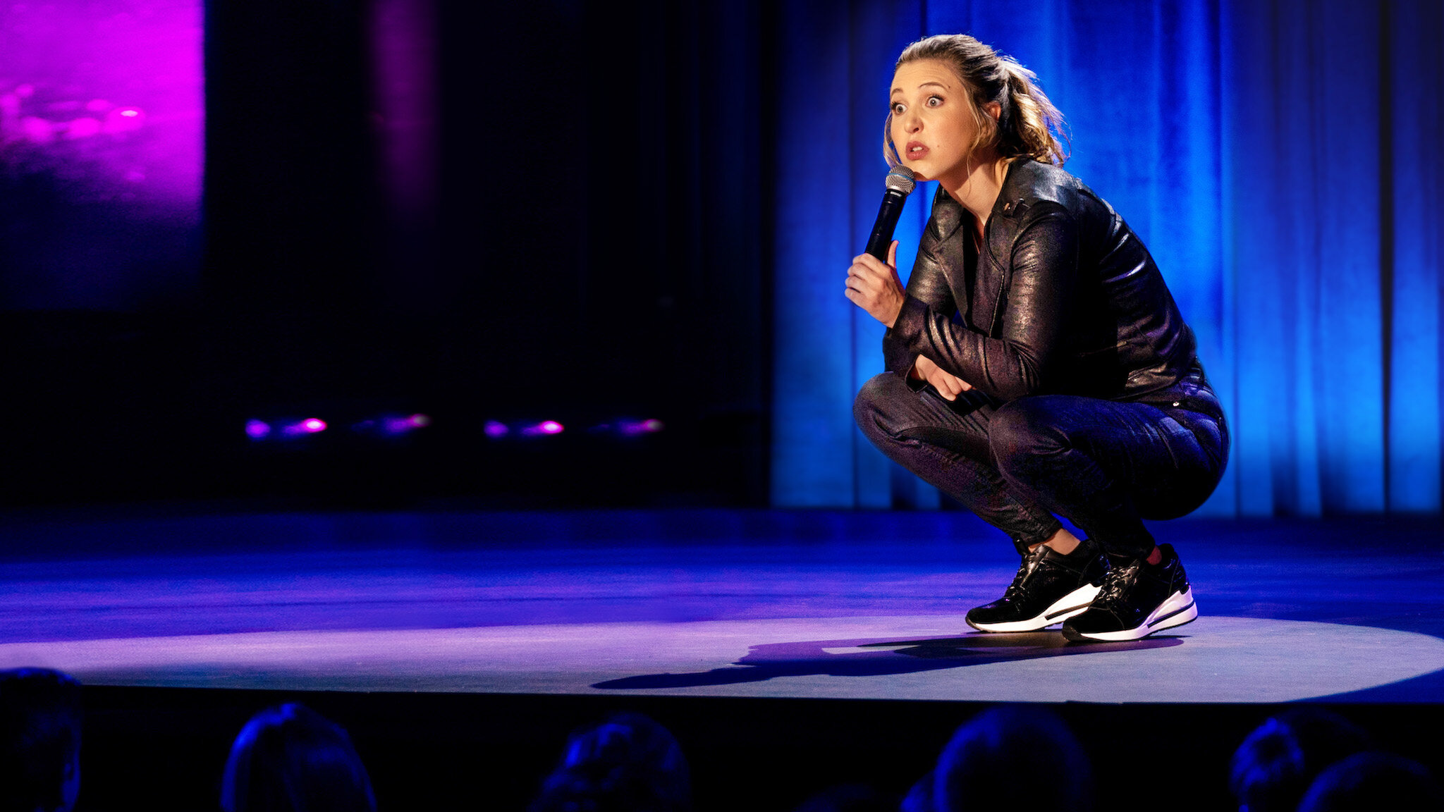 Taylor Tomlinson crouches during her comedy special, 'Quarter-Life Crisis.'