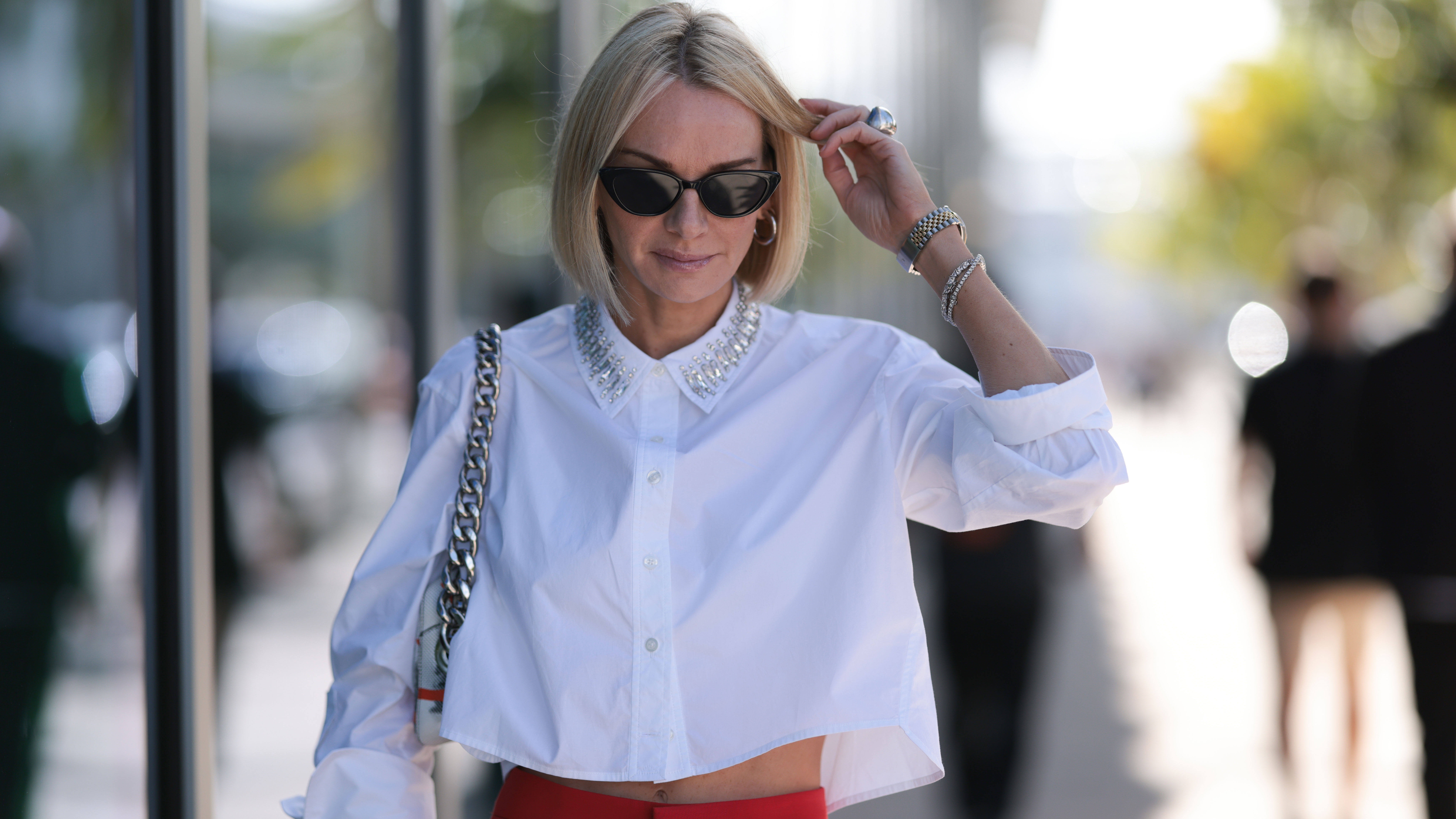 MIAMI, FLORIDA - DECEMBER 07: Lena Johnson seen wearing black sunglasses, silver earrings, white cotton cropped shirt / blouse with rhinestones pattern collar, red long pants and silver watch, on December 07, 2023 in Miami, Florida. (Photo by Jeremy Moeller/Getty Images)