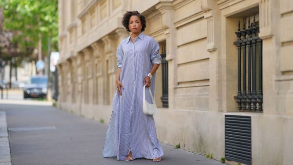 PARIS, FRANCE - MAY 20: Ellie Delphine wears earrings from Monica Vinader, silver jewelry, a beaded necklace from Lie Studio, a blue and white long maxi shirt dress with stripes from The Frankie Shop, a white leather bag from The Row, a cuff bracelet from Tiffany, white shoes, during a street style fashion photo session, on May 20, 2024 in Paris, France. (Photo by Edward Berthelot/Getty Images)