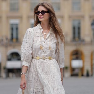 PARIS, FRANCE - JUNE 14: Segolene Hyppolite wears sunglasses, a white mini pleated and gathered summer dress with floral embroidery and long sleeves from Anne Fontaine, a rope belt from Anne Fontaine, a raffia bag from Vanessa Bruno, during a street style fashion photo session, on June 14, 2024 in Paris, France. (Photo by Edward Berthelot/Getty Images)