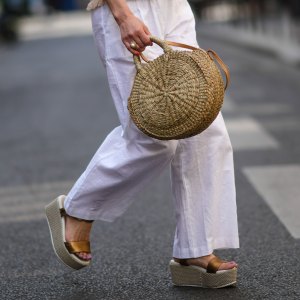 PARIS, FRANCE - MAY 10: Maria Rosaria Rizzo wears a white latte t-shirt with fringed borders, a beige wickers handbag from Guerlain, a gold large bracelet, gold rings, high waist white wide legs linen pants, during a street style fashion photo session, on May 10, 2022 in Paris, France. (Photo by Edward Berthelot/Getty Images)