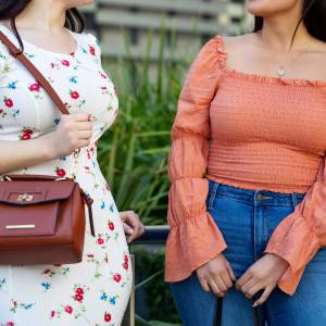Cropped shot of two females friends standing outdoors and talking. Women in casual clothing chatting in the city.