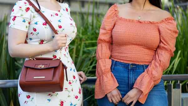 Cropped shot of two females friends standing outdoors and talking. Women in casual clothing chatting in the city.