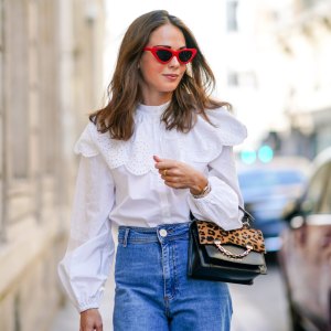 Therese Hellström wears red Celine sunglasses, a white shirt / blouse from H&M with large ruffled collar, a black leather Karl Lagerfeld bag with a chain and brown leopard print, blue denim flared jeans from Zara, on September 15, 2020 in Paris, France.