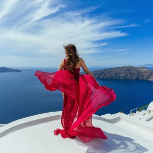 Woman in red dress aerial on the roof of island Santorini