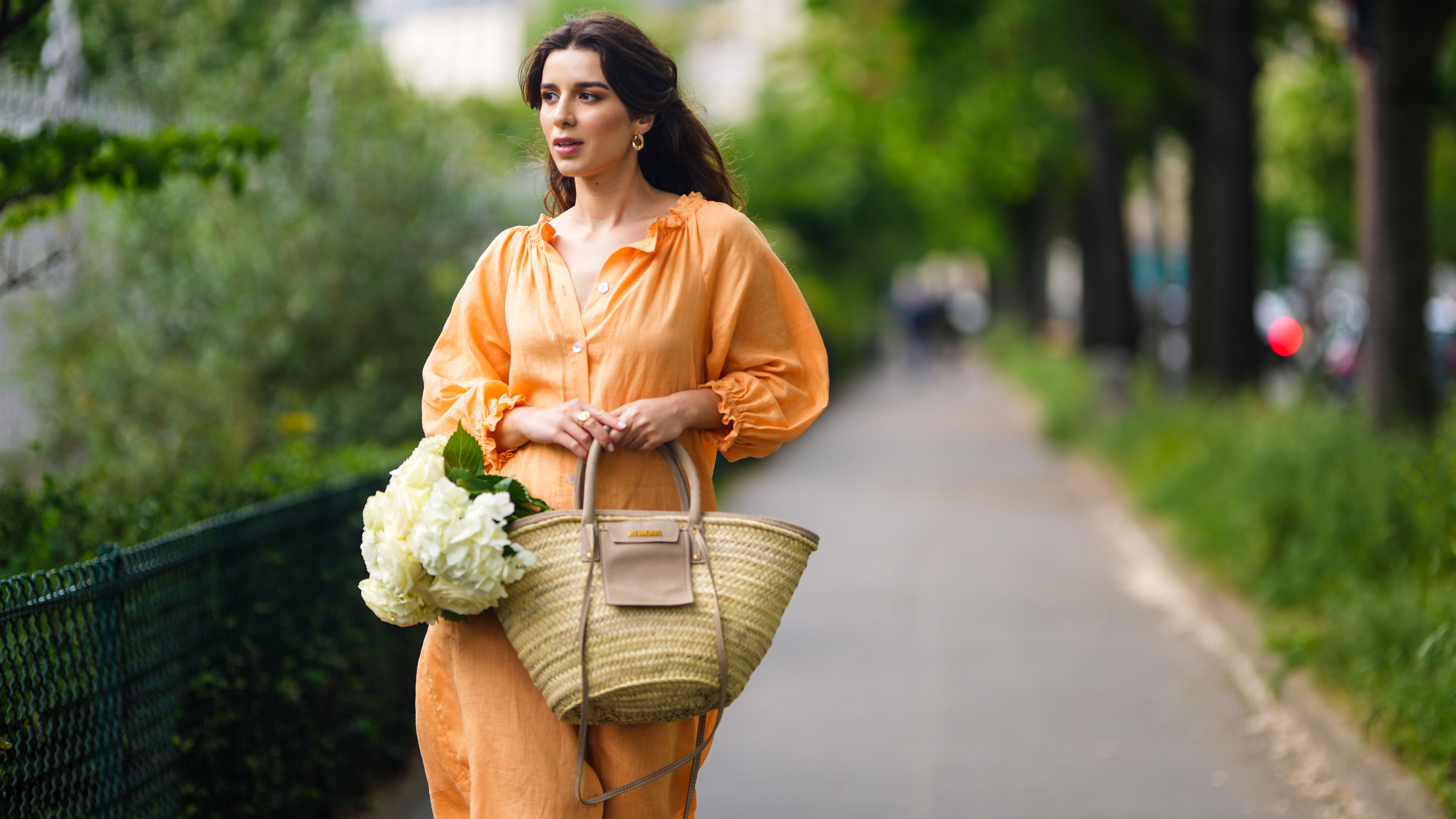PARIS, FRANCE - MAY 10: Ketevan Giorgadze @katie.one wears gold earrings, a long buttoned coral loungewear linen The Sleeper dress with puffy sleeves, gold rings, a wicker with brown shiny leather detail Le Panier Soleil Jacquemus tote-bag, on May 10, 2021 in Paris, France. (Photo by Edward Berthelot/Getty Images)