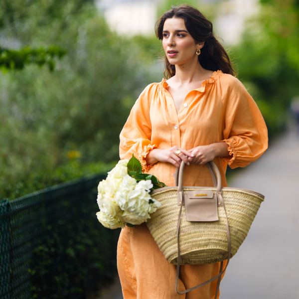PARIS, FRANCE - MAY 10: Ketevan Giorgadze @katie.one wears gold earrings, a long buttoned coral loungewear linen The Sleeper dress with puffy sleeves, gold rings, a wicker with brown shiny leather detail Le Panier Soleil Jacquemus tote-bag, on May 10, 2021 in Paris, France. (Photo by Edward Berthelot/Getty Images)