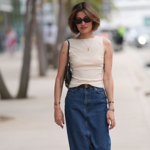 MIAMI, FLORIDA - DECEMBER 08: Michelle Fleur seen wearing Saint Laurent black sunglasses, cream white sleeveless top, gold letter necklace, Louis Vuitton brown canvas logo pattern belt, dark blue denim / jeans long skirt, Bottega Veneta black leather purse / shoulder bag, Cartier Panthère silver / gold bi-color watch, on December 08, 2023 in Miami, Florida. (Photo by Jeremy Moeller/Getty Images)