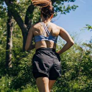 Mid adult woman running in the forest on a sunny day