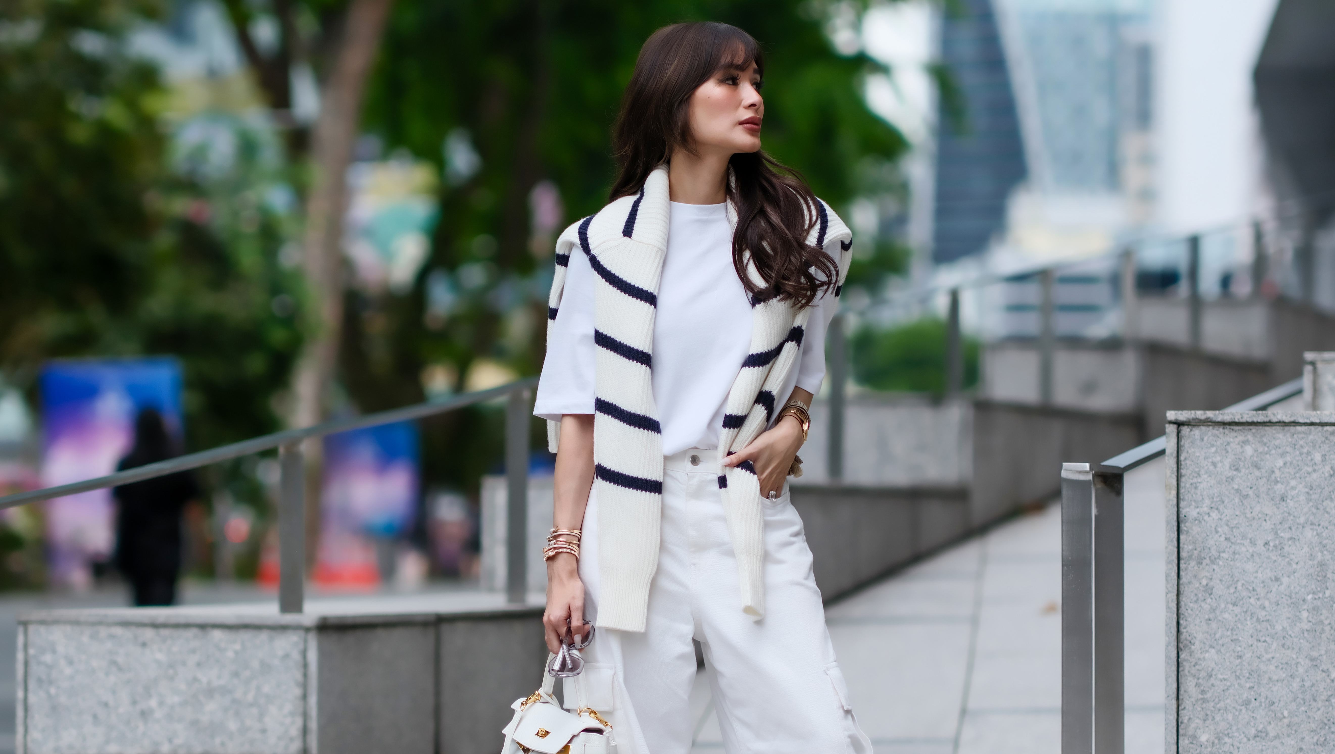 SINGAPORE, SINGAPORE - NOVEMBER 14: Heart Evangelista wears a dark navy blue and white wool knit pullover from Joshua's x Smiley, a white t-shirt from Frankie Shop, a white leather Hermes bag, white cargo wide-leg flared pants from Cos, Chanel shoes, during a street style fashion photo session, on November 14, 2023 in Singapore. (Photo by Edward Berthelot/Getty Images)