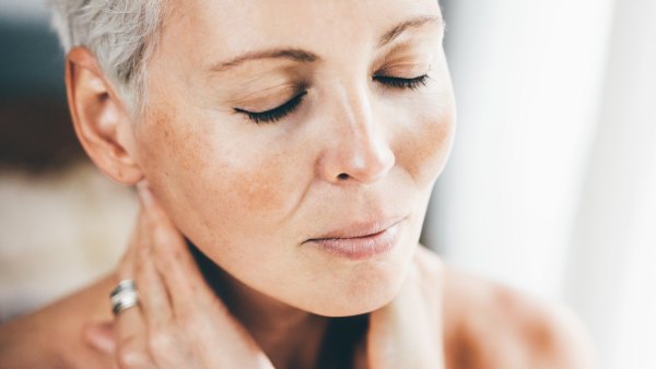 Older woman touching her skin in the mirror