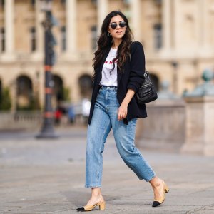 PARIS, FRANCE - FEBRUARY 25: Camille Grandguillote wears sunglasses, a black blazer jacket from Sezane, a black leather bag from Kate Lee, a white t-shirt from "Pas le Time", blue denim jeans pants from Asos, Chanel beige and black slingback shoes, on February 25, 2021 in Paris, France. (Photo by Edward Berthelot/Getty Images)