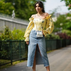 PARIS, FRANCE - APRIL 28: Ketevan Giorgadze @katie.one wears a blue denim midi slit skirt from Zara, a yellow floral print puff sleeve vintage ruffled silk open shoulder corset top with a tie string back from Overtheseadress, a Le chiquito white mini leather bag from Jacquemus, vintage earrings, white leather slingback pointed pumps from Raye, a gold chain necklace from For Art’s Sake, on April 28, 2021 in Paris, France. (Photo by Edward Berthelot/Getty Images)