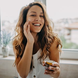 Young woman applies facial cream - stock photo