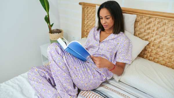 Woman reading book in bed - stock photo