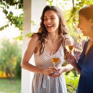 Serene female Caucasian friends, drinking wine while having a casual conversation during summer garden party