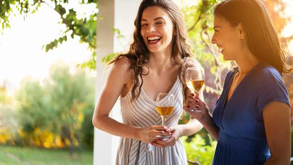 Serene female Caucasian friends, drinking wine while having a casual conversation during summer garden party