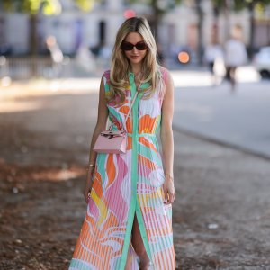 Mandy Bork seen wearing brown sunglasses from Tom Ford, silver earrings, a colorful buttoned / pleated / sleeveless long dress from Emilio Pucci, a pale pink leather Hermes Kelly mini bag, a gold diamond Cartier Love bracelet, a gold Cartier Juste Un Clou bracelet and white creme sandals from Chanel, during Paris Fashion Week - Haute Couture Fall Winter 2022 2023, on July 06, 2022 in Paris, France.