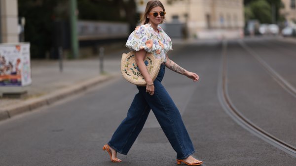 Aline Kaplan wearing Baum & Pferdgarten wide leg blue denim pants, & other stories white flower pattern cropped blouse and orange summer heels and Mango orange black shades on June 06, 2023 in Berlin, Germany.