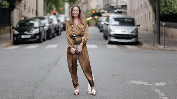 Alba Garavito Torre wears a khaki green long silk jumpsuit from Zara, a brown leather envelope clutch with gold details from Octogony, a brown and white penny loaffers sling backs from Miu Miu, a long pearl and gold necklace from Sempiterno Paris, during a street style fashion photo session, on June 10, 2024 in Paris, France.