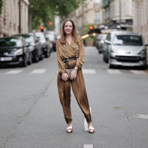 Alba Garavito Torre wears a khaki green long silk jumpsuit from Zara, a brown leather envelope clutch with gold details from Octogony, a brown and white penny loaffers sling backs from Miu Miu, a long pearl and gold necklace from Sempiterno Paris, during a street style fashion photo session, on June 10, 2024 in Paris, France.
