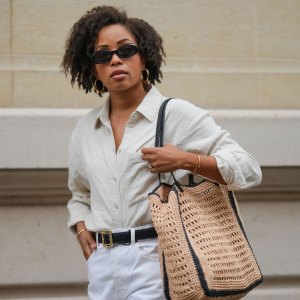 PARIS, FRANCE - MAY 08: Ellie Delphine wears a full Mango look, sunglasses, golden earrings, a white linen shirt, a black leather belt with golden buckle, golden bracelets, a white ripped denim shorts, a large brown raffia bag, during a street style fashion photo session, on May 08, 2024 in Paris, France. (Photo by Edward Berthelot/Getty Images)