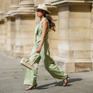 PARIS, FRANCE - MAY 29: Angela Gonzalez wears a beige suede Lack Of Color hat, earrings, a black off shoulder top, a pale green buttoned blazer jacket sleeveless from Nasty Gal, pale green matching Nasty Gal flared pants, a gold chain bracelet, a beige shiny leather Mango handbag, brown shiny leather strappy hells Na-Kd sandals, on May 29, 2021 in Paris, France. (Photo by Edward Berthelot/Getty Images)