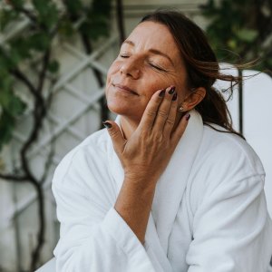 Smiling woman applying face cream - stock photo
